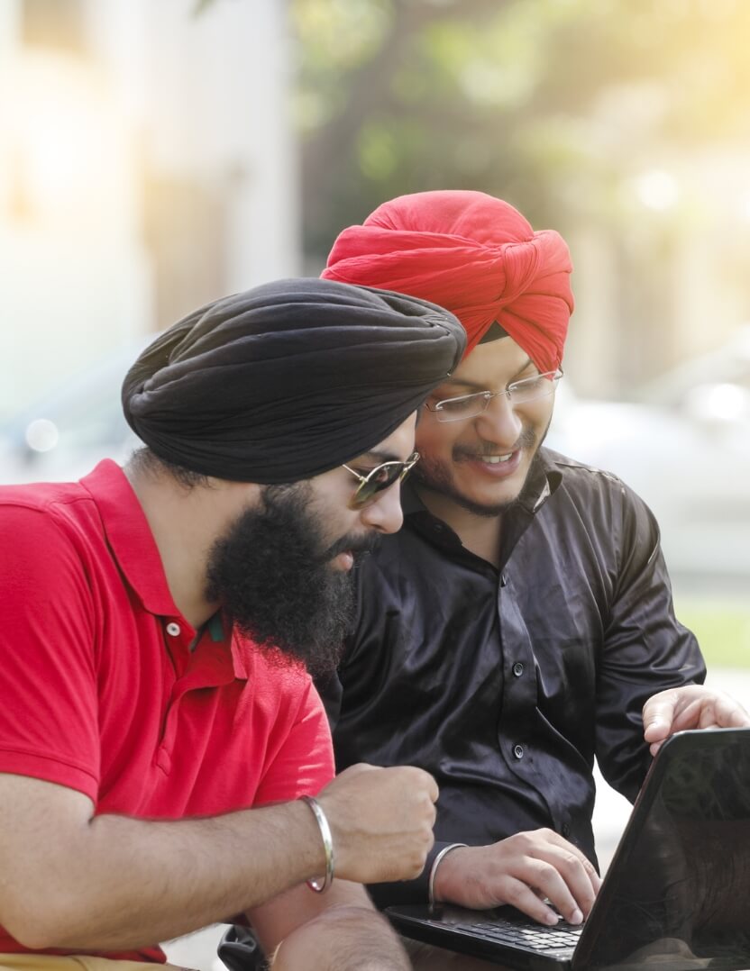 Two men smiling, using a laptop